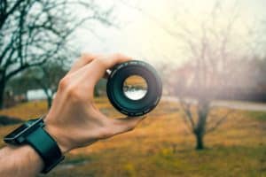 man holding a camera lens to the world instead of asking why is life so unfair