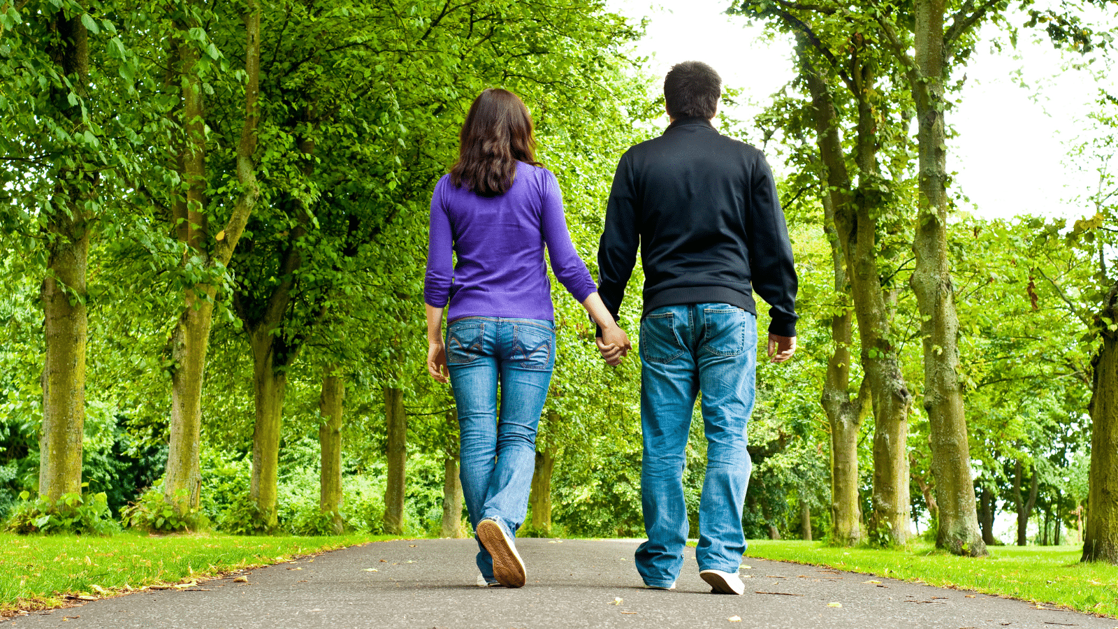 Couple holding hands and walking in a park.