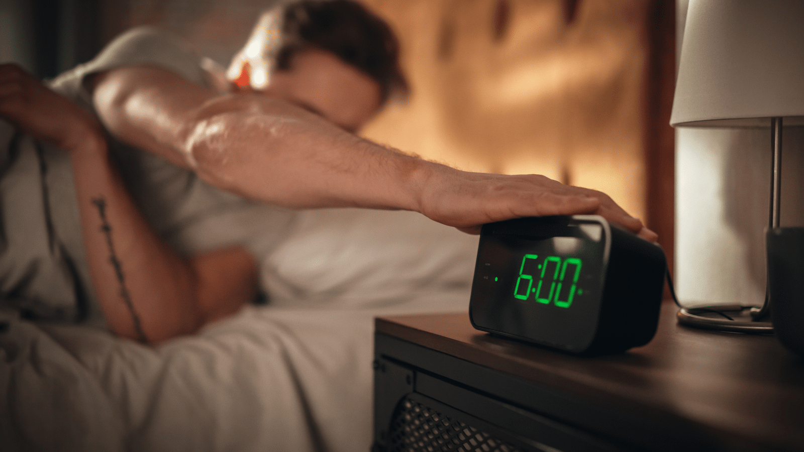 Man wakes up and turns off the alarm clock to wake up early for a productive start of the day.