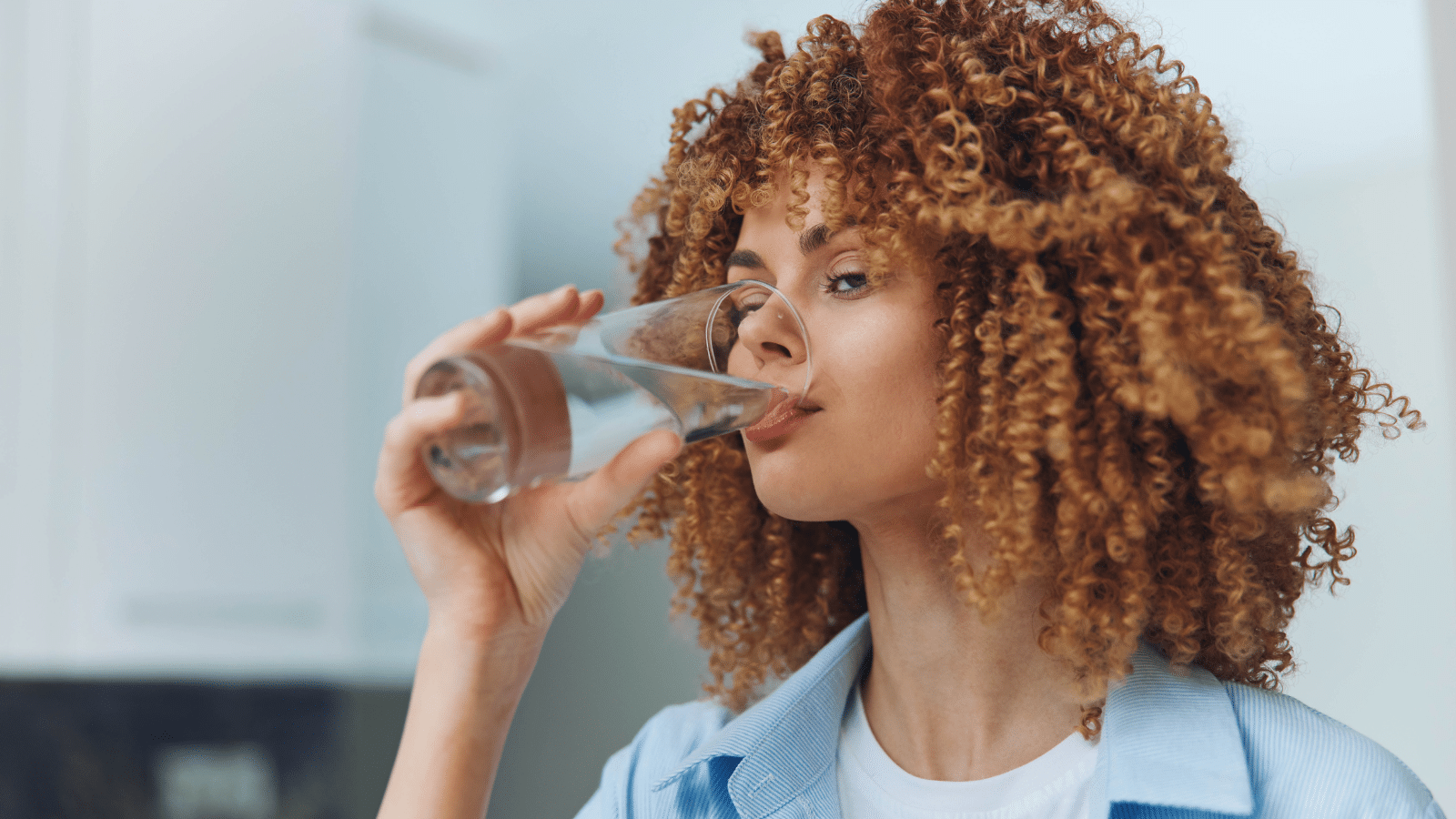 Woman staying hydrated by drinking water in the comfort of her home kitchen.