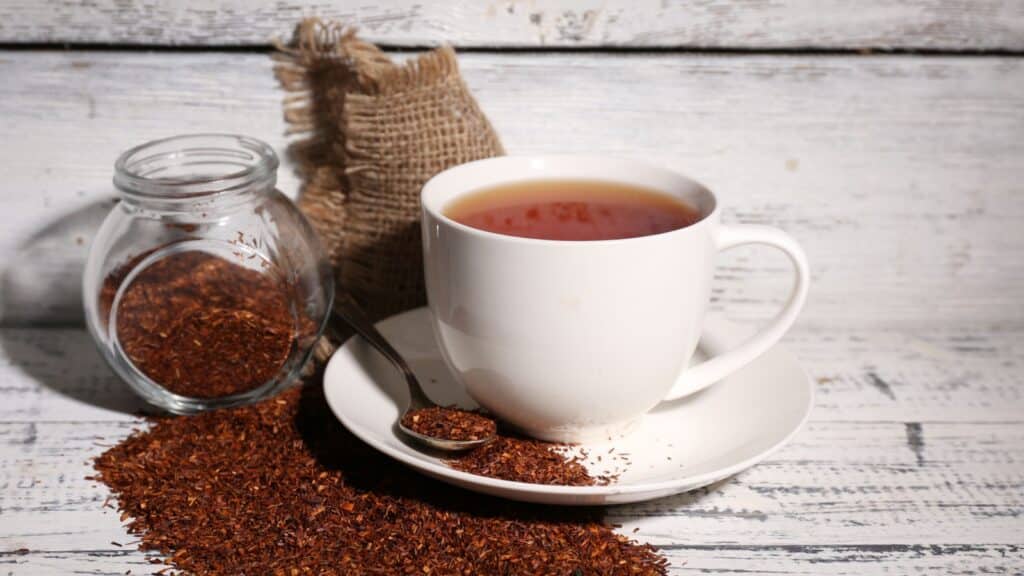 Cup of tasty rooibos tea, on old white wooden table.