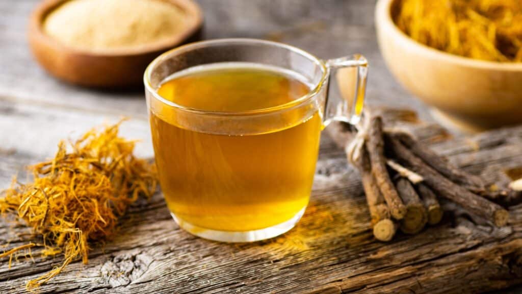 Glass cup of licorice tea with licorice root and fiber on rustic background, alternative medicine ( glycyrrhiza glabra ).
