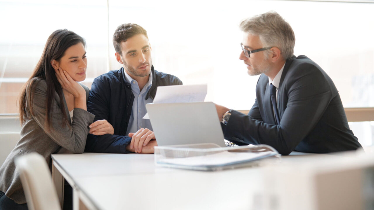 Young couple meeting financial advisor for home investment. Money, wealth, family planning.