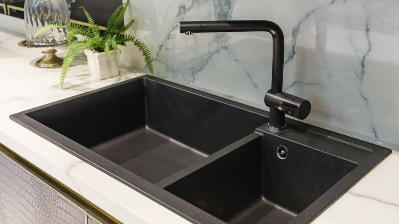 Black kitchen sink and Tap water in the kitchen. The interior of the kitchen room of the apartment. Built-In Appliances. Kitchen Appliance. Domestic Appliances
