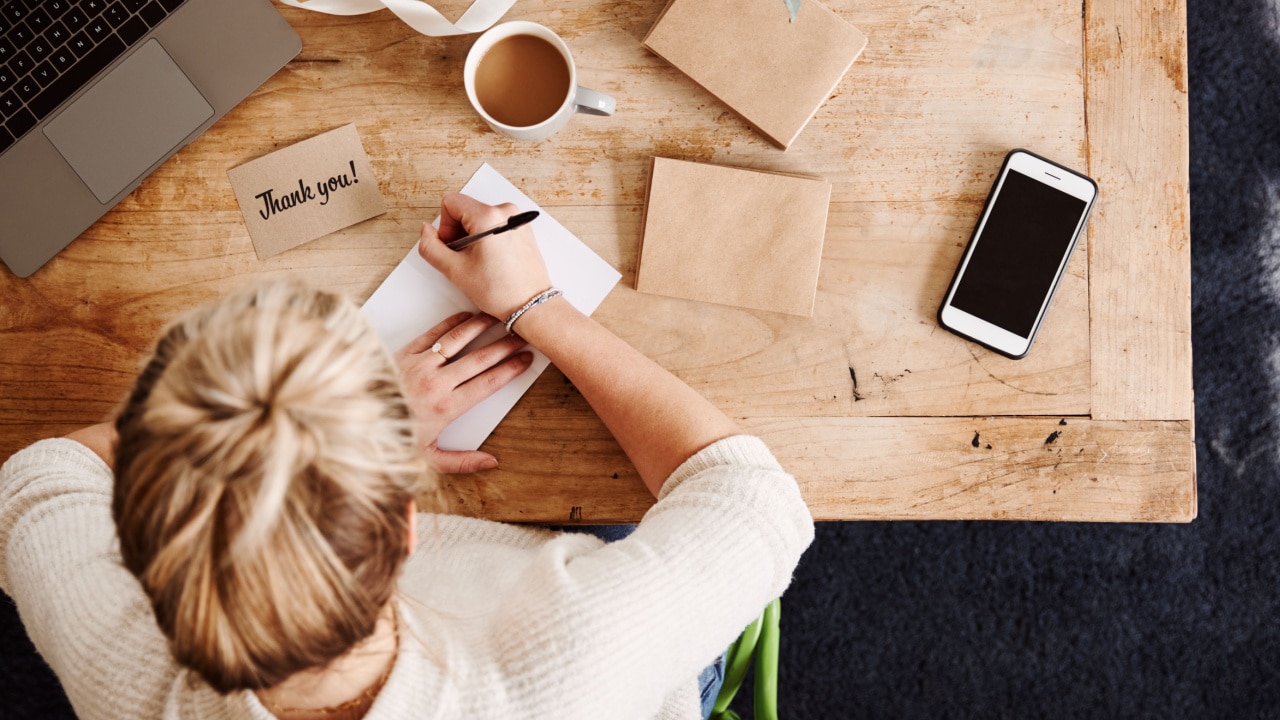 overhead view of a woman writing thank you cards on her desk