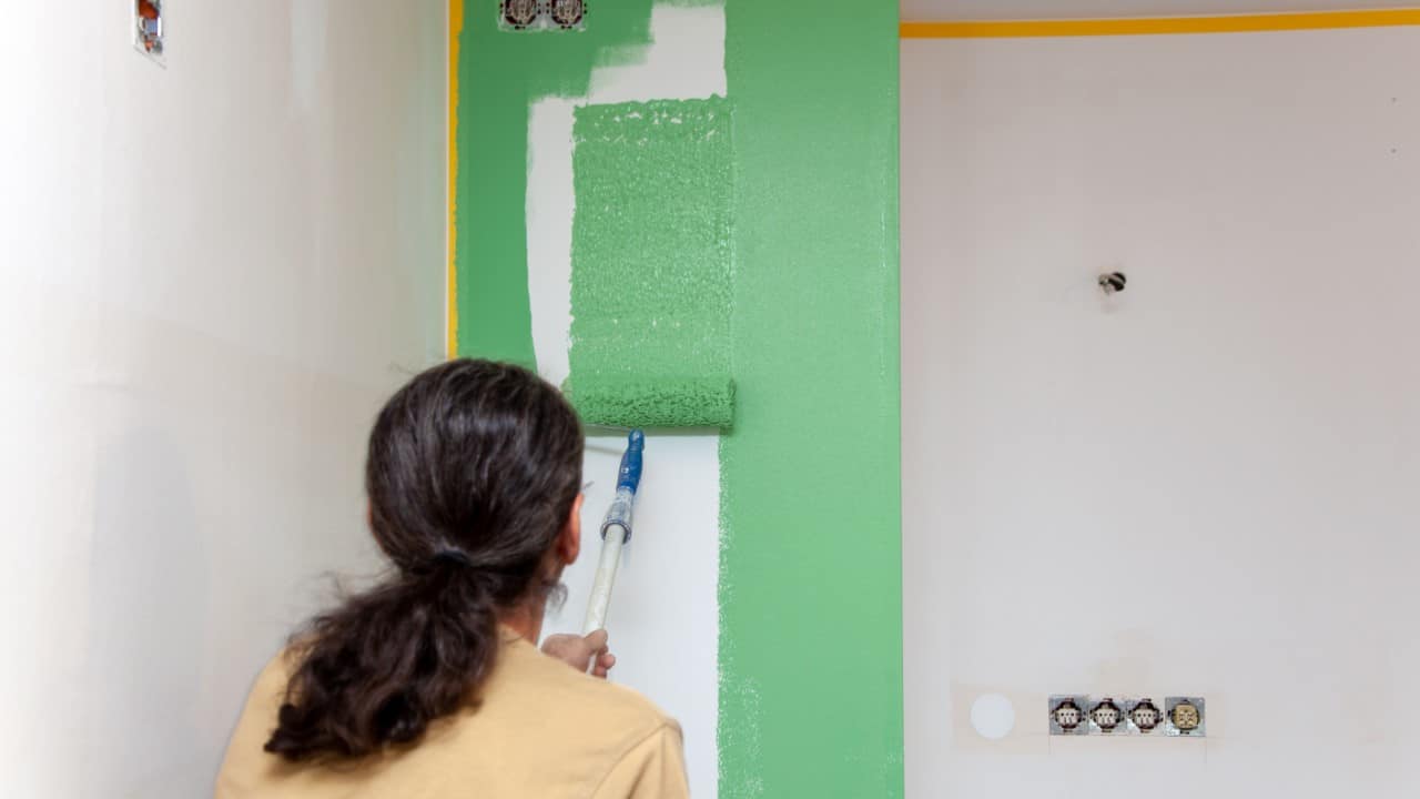 Person using a roller to paint a wall