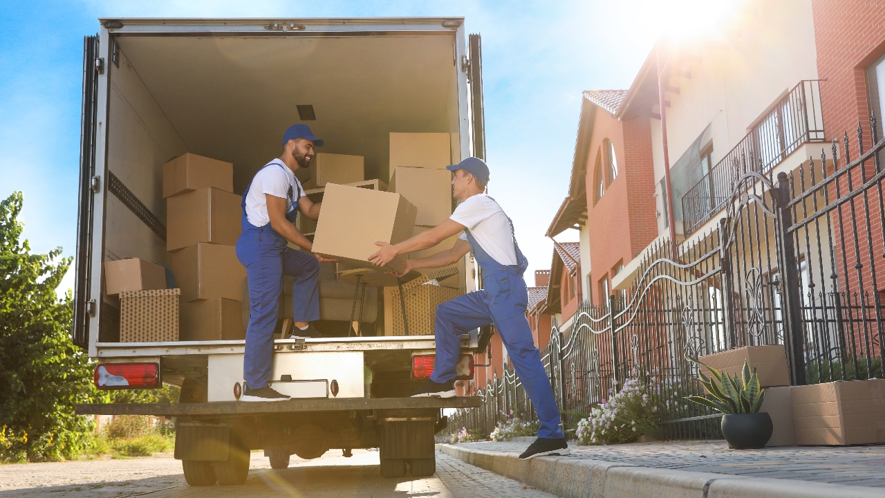 Workers unloading boxes from van outdoors. Moving service, movers, professional