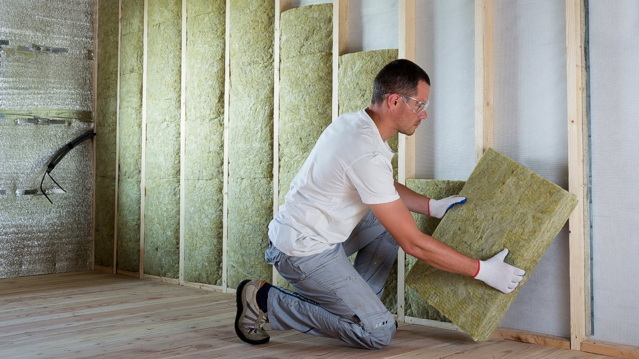 Man installing insulation in walls of a residential home.