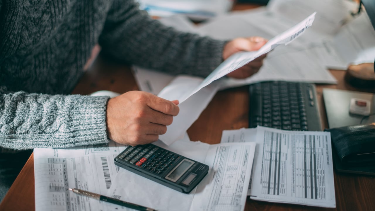 Close-up of male hands with a utility bill, a lot of checks and a calculator on the table. The man considers the costs of gas, electricity, heating.