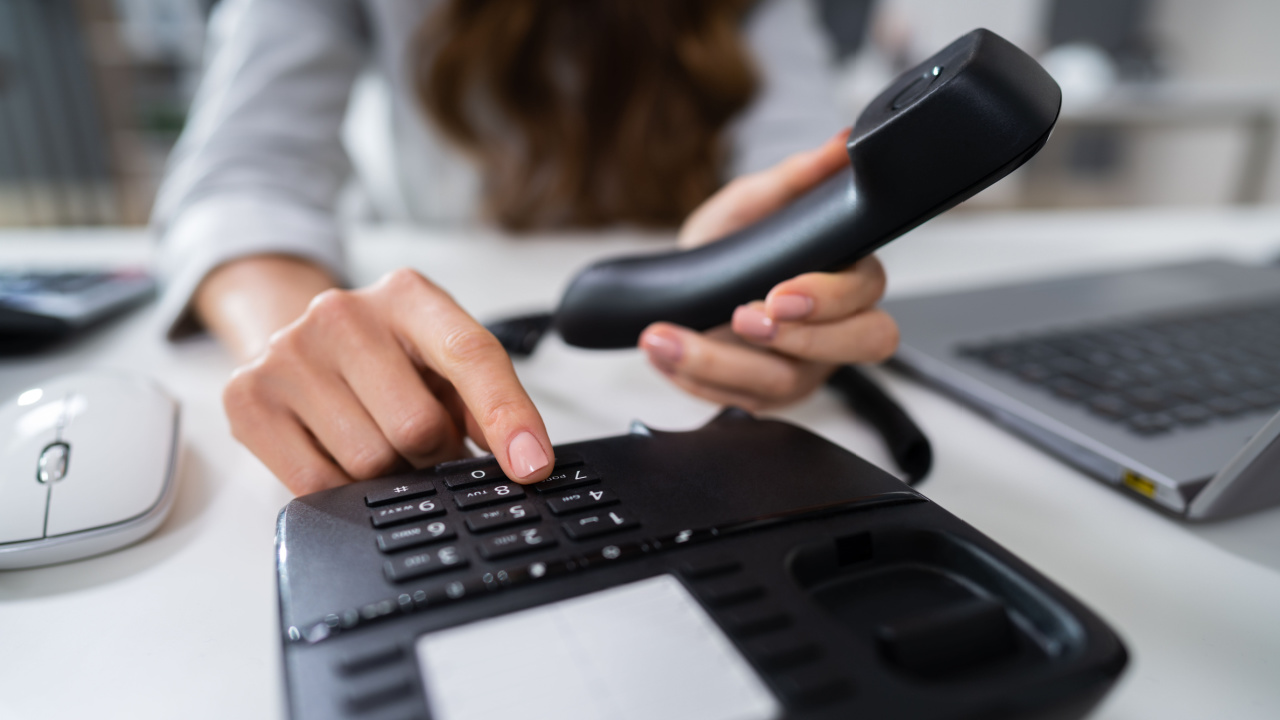 woman dialing an office phone, work phone