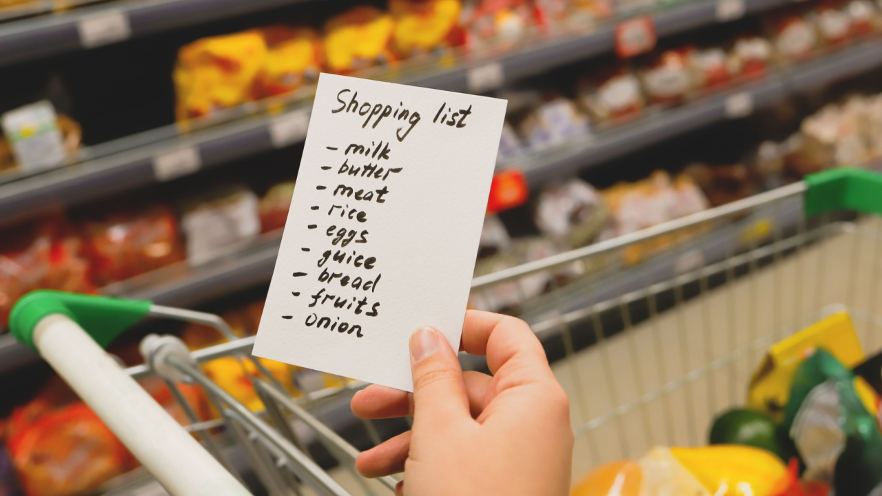 Woman with notebook in grocery store, closeup. Shopping list on paper. Check purchases in grocery cart.