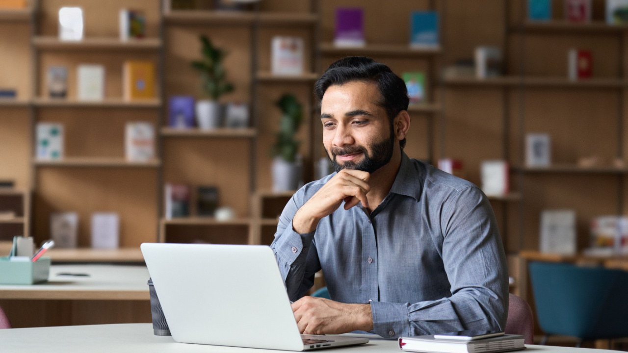 Man sitting at computer learning about money management, investments, liquidity, and wealth building, and financial literacy knowledge