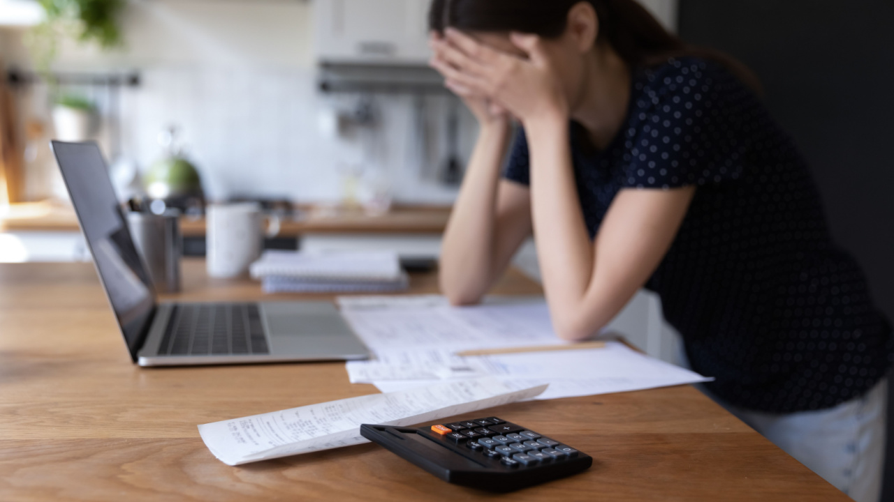 bankruptcy, Close up view calculator and bills on table, desperate young woman on background, makes expenses and earnings analysis feels tired and disappointed. Lack of money, overspend, debt, financial troubles