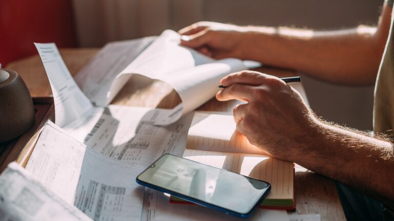 Close-up of men's hands with a calculator and utility bills.