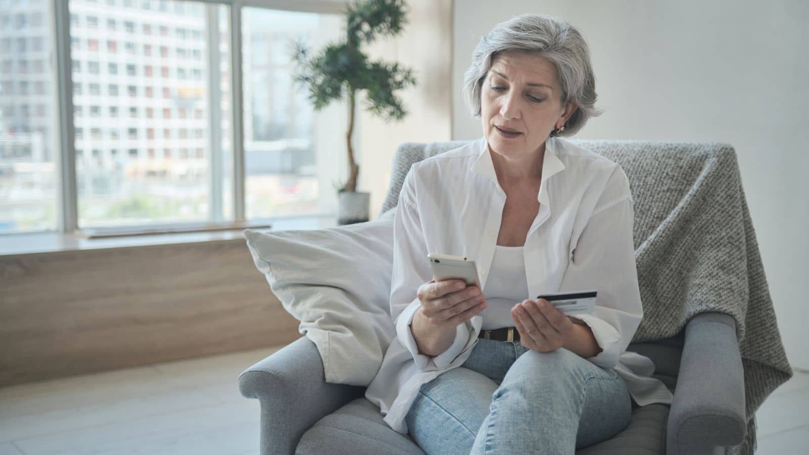 older lady paying for something with credit card on phone.