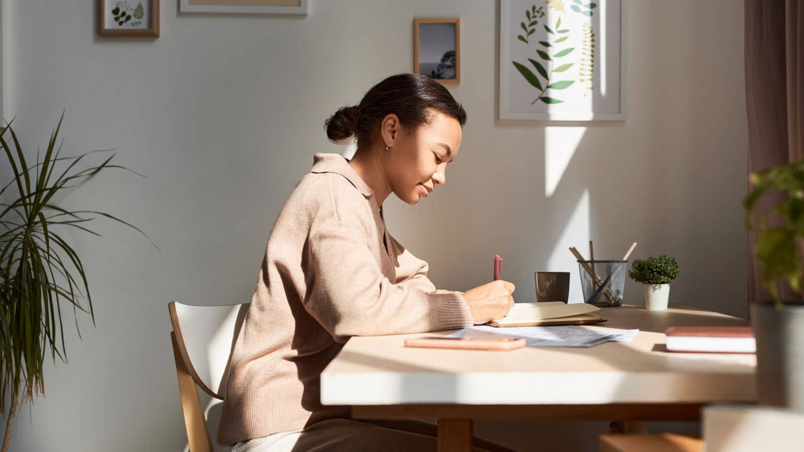 woman writing in journal with sunrays.