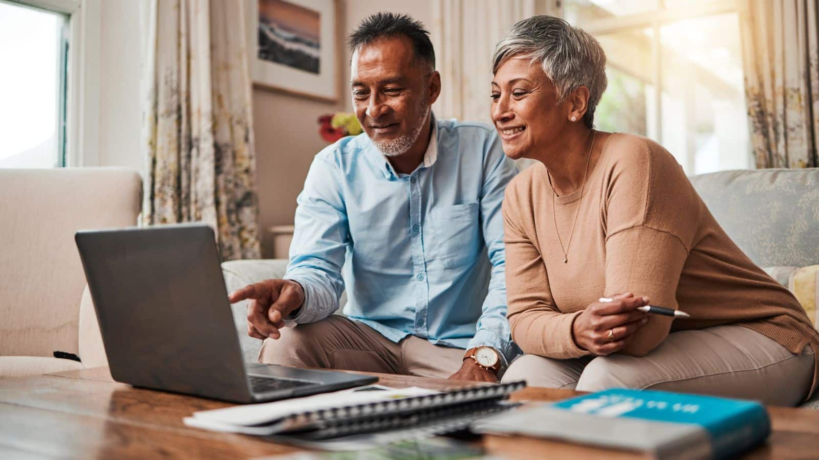 Couple sitting on sofa using laptop for planning finance, retirement funding and investment.