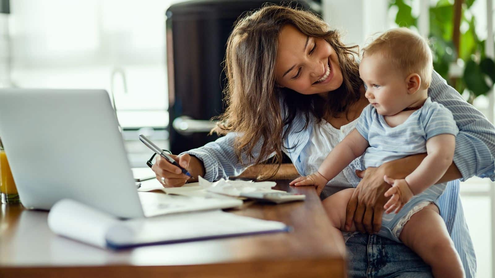 Happy mother talking to her baby while working at home.