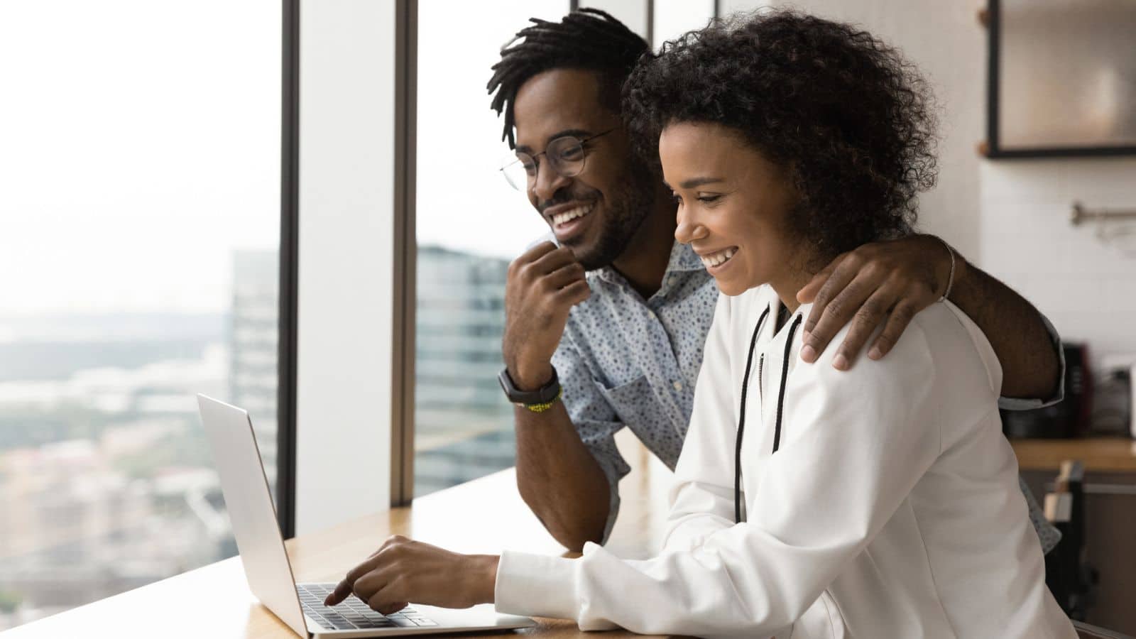 Happy couple use laptop at home together