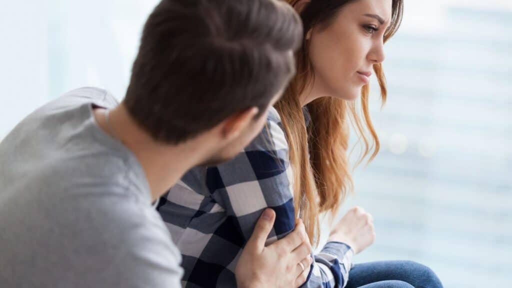 Caring man comforting upset wife after fight.