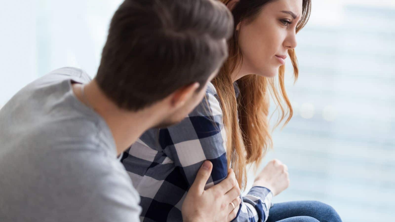 Caring man comforting upset wife after fight.