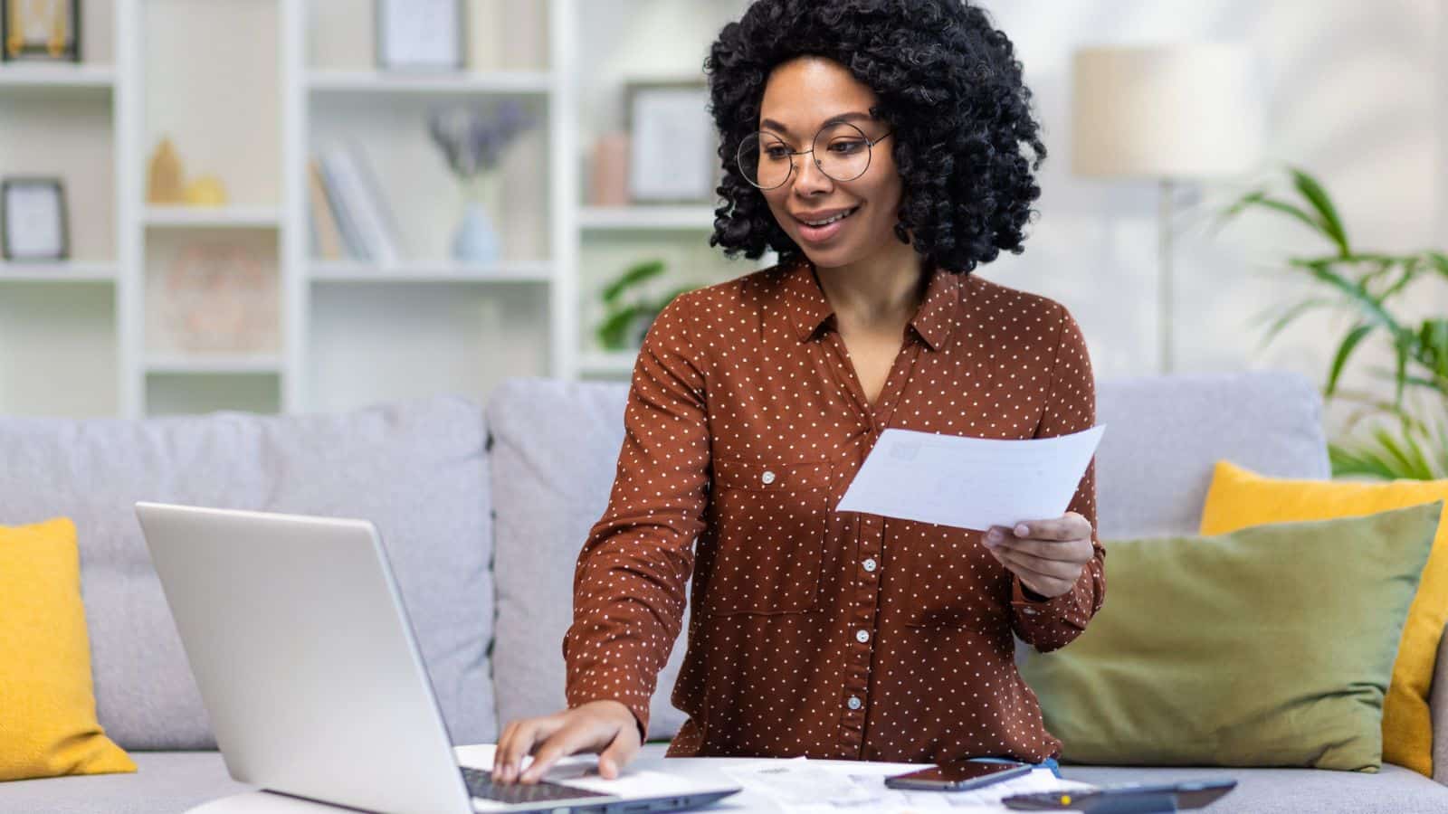 Young woman smiling working on computer and paying bills.