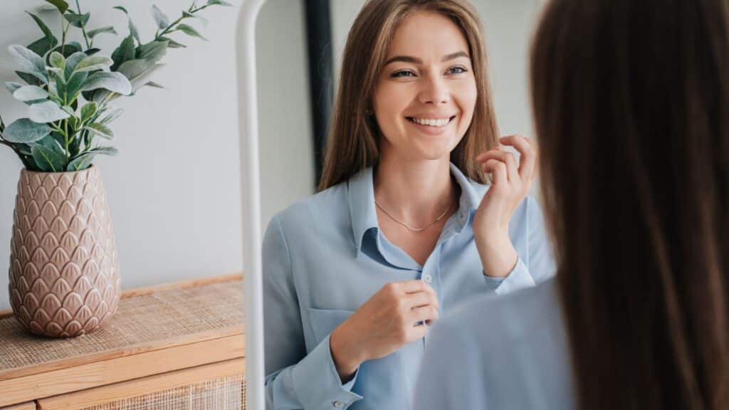 Happy young woman smiling in mirror.