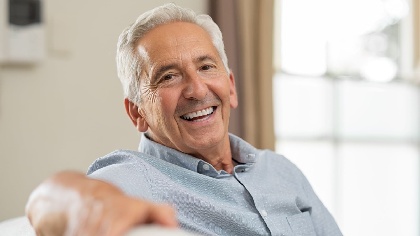 Man smiling relaxing on sofa enjoying retirement.