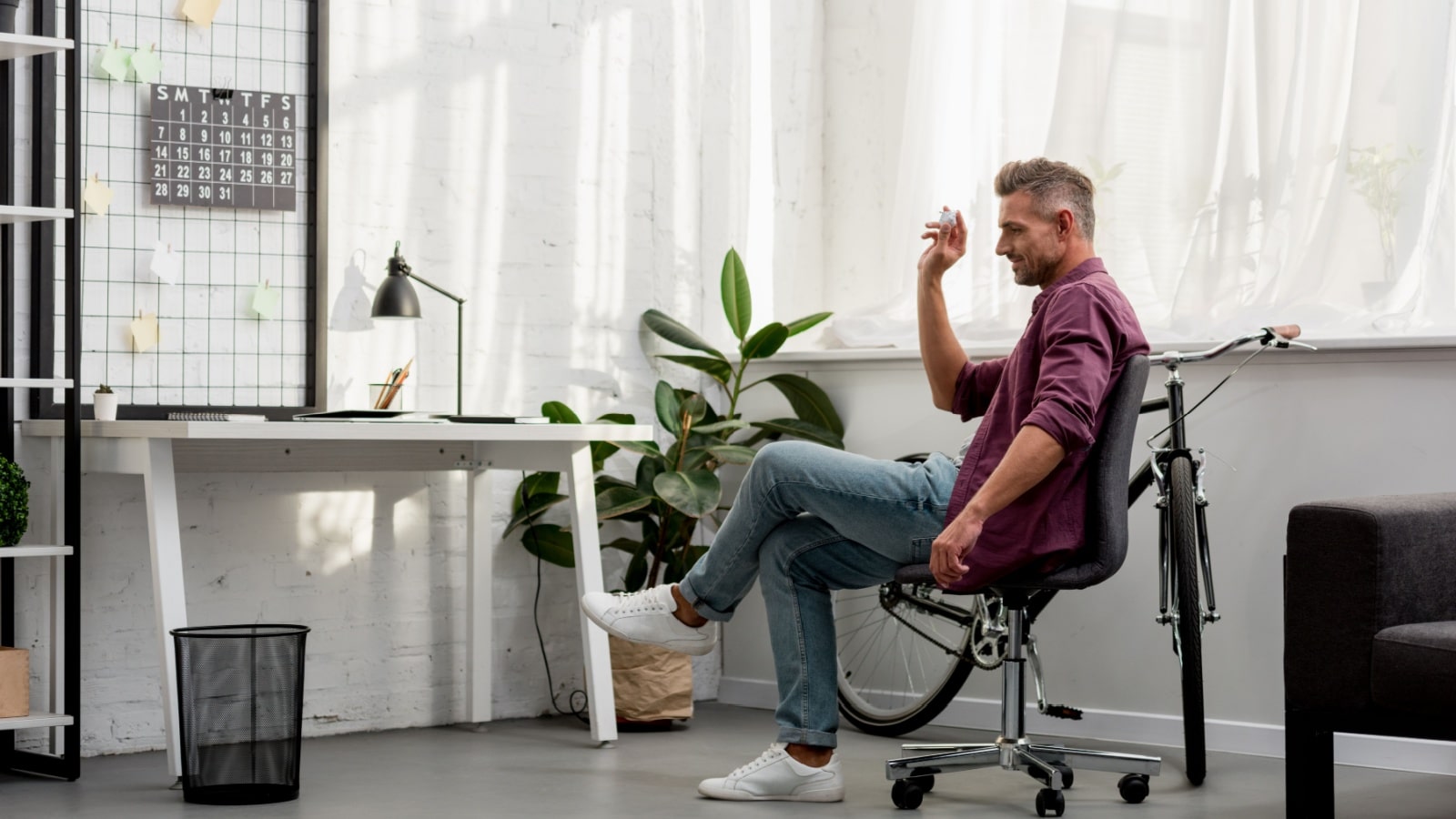 Man throwing trash in basket in home office.