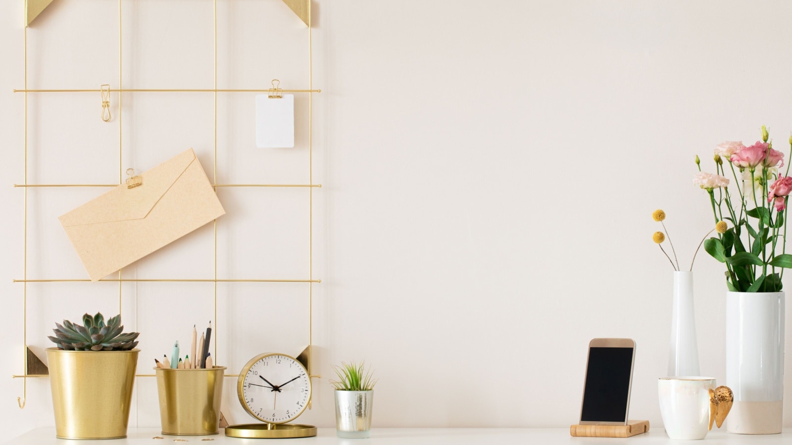 Modern office desk with gold accessories clock plant pens.