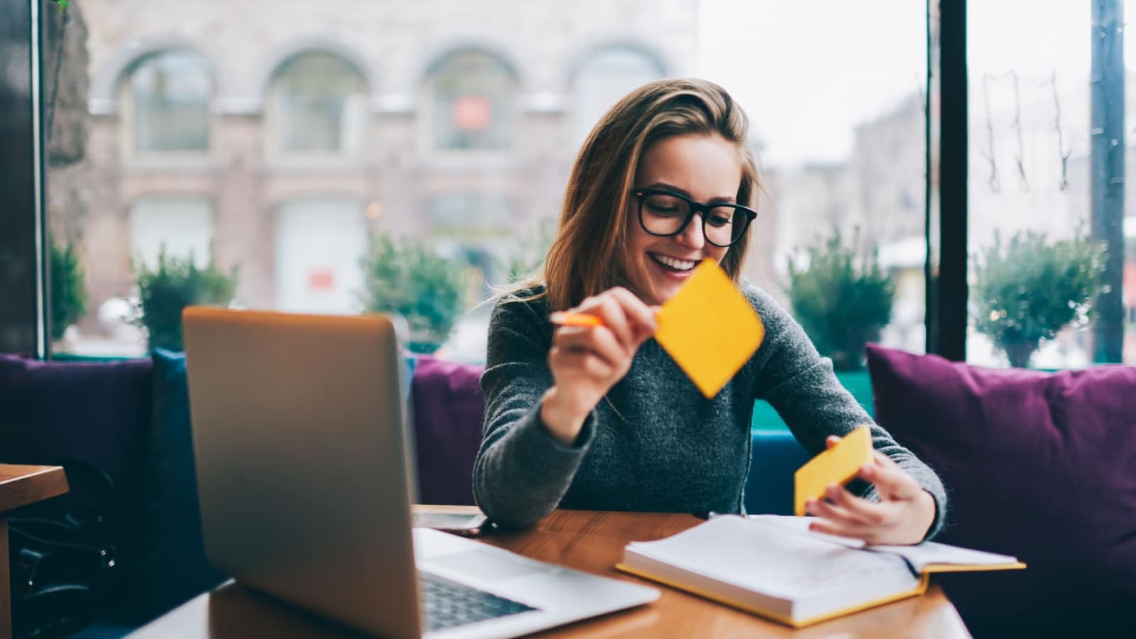 Positive young woman smiling being productive at computer sticky notes book.