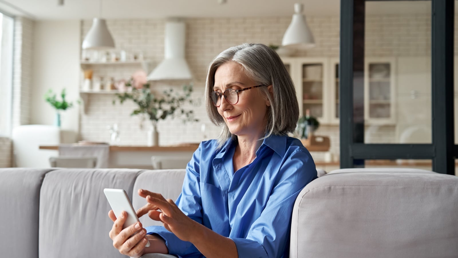 Relaxed mature older woman holding smartphone.