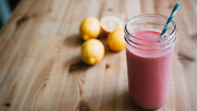 Smoothie with fruit in background.