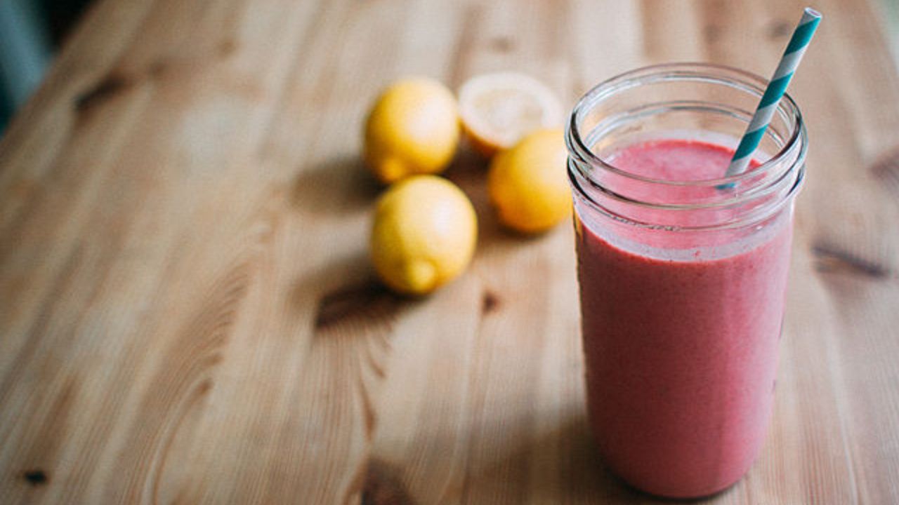 Smoothie with fruit in background.