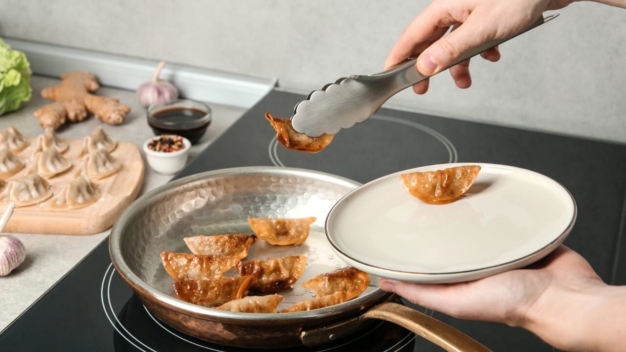 Kitchen tongs, cooking, potstickers, dumplings, prepare, serve, chef, cook, stove, meal, dinner, food, plate