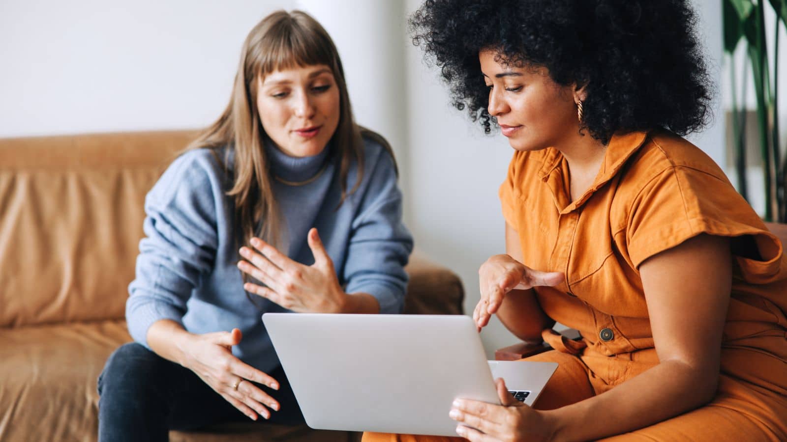 Two business women having a discussion while looking at a laptop screen.