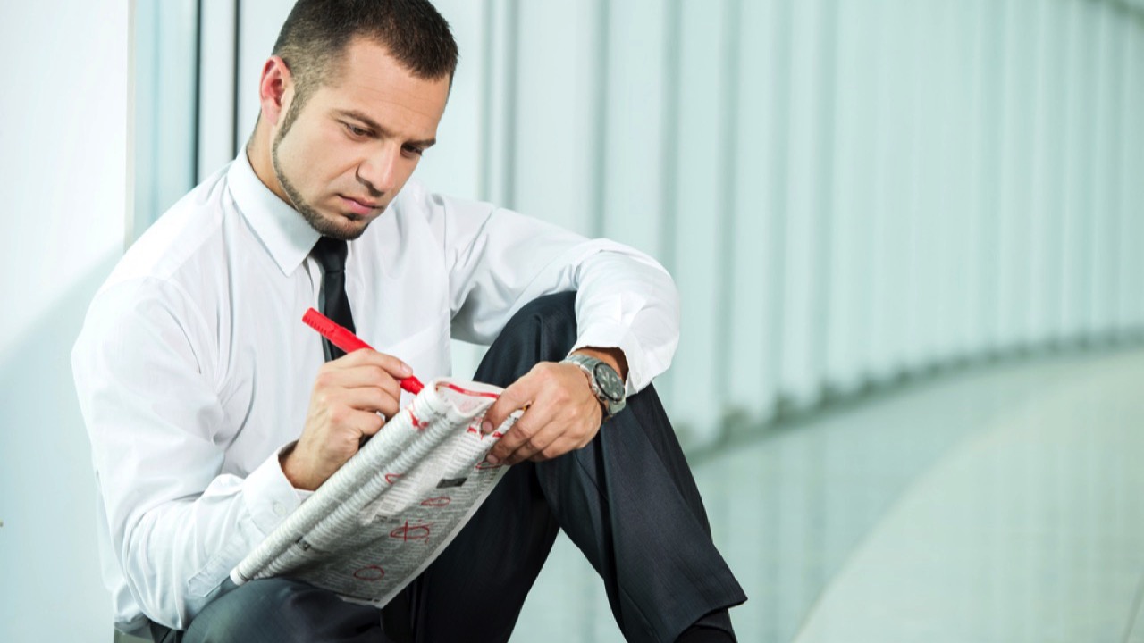 Upset man searching for job in newspaper