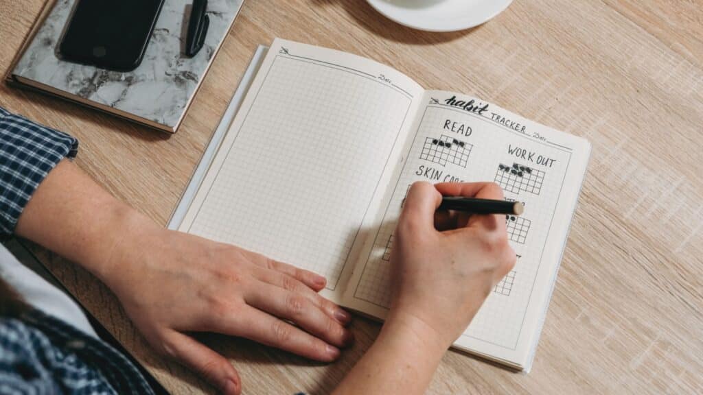 Woman cross off day with routine in her Habit Tracker in a Bullet Journal.