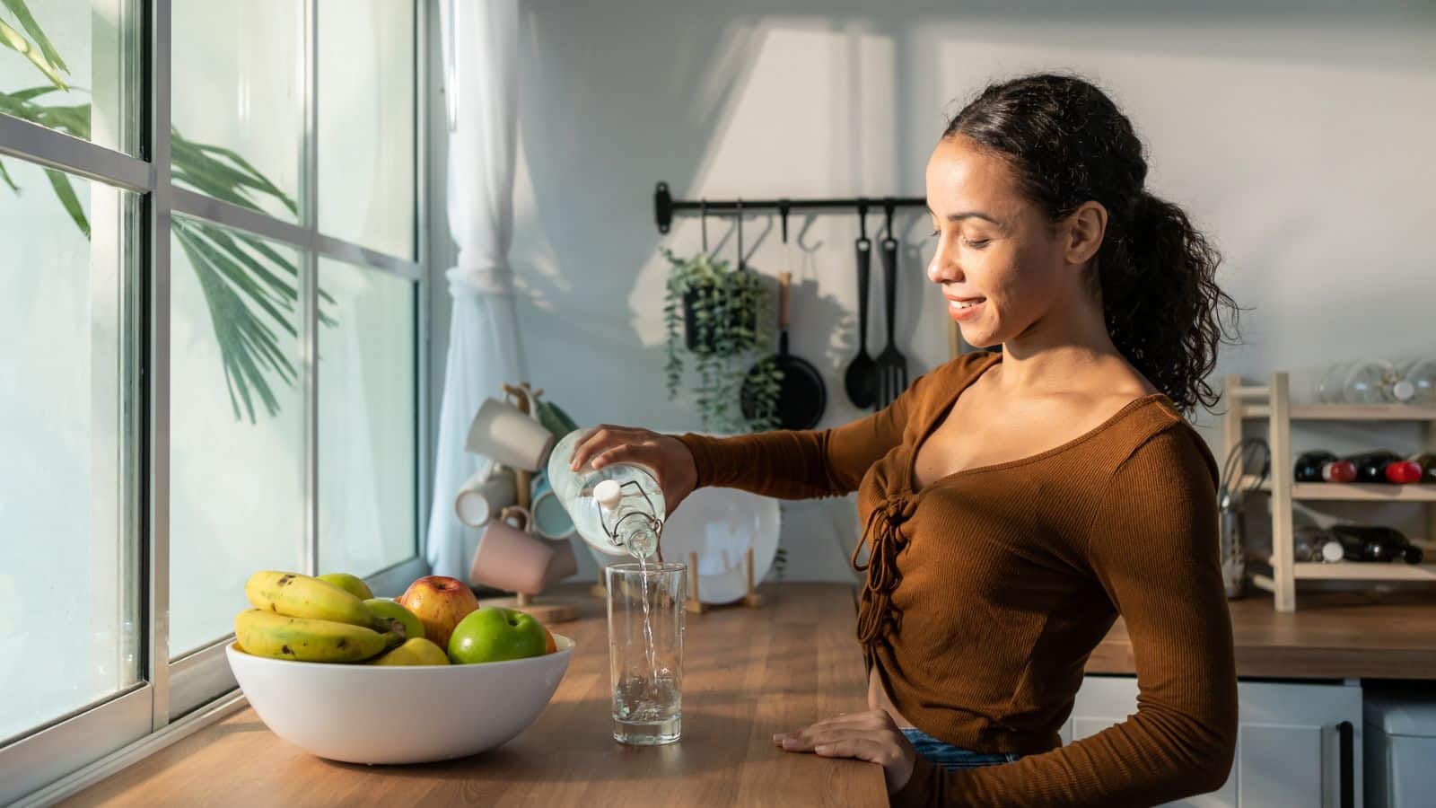 Woman drinking water in kitchen.
