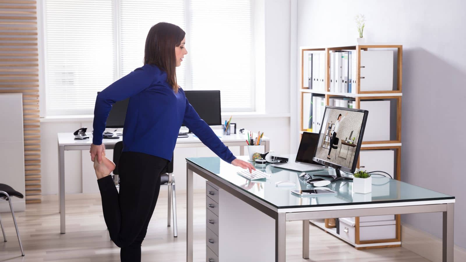 Woman stretching and doing yoga at desk.