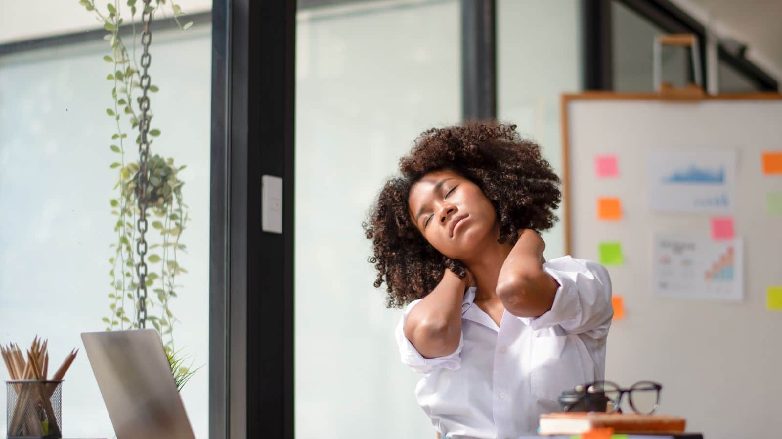 Woman stretching neck and checking posture at work.
