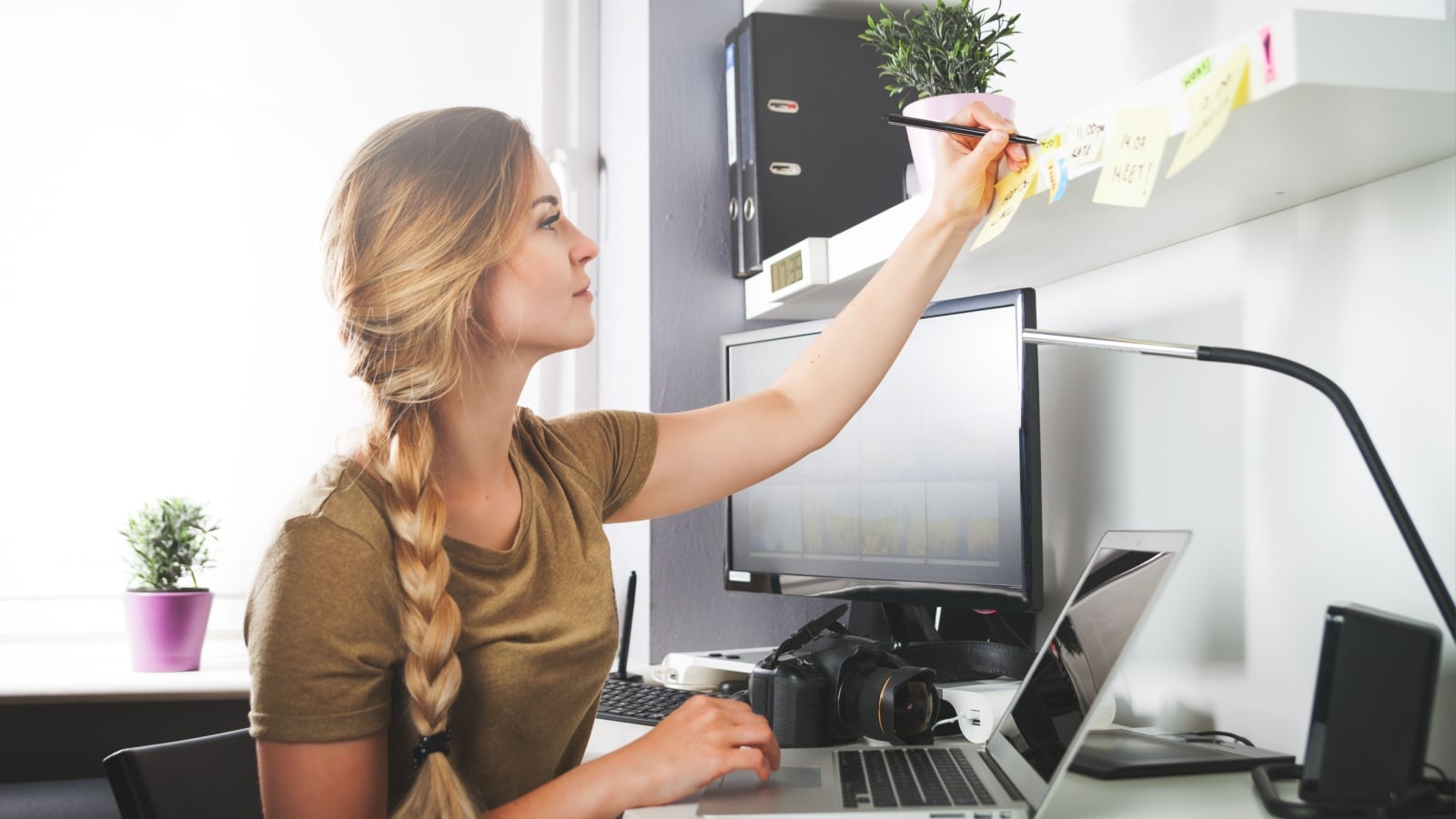 Woman writing on sticky notes at desk.