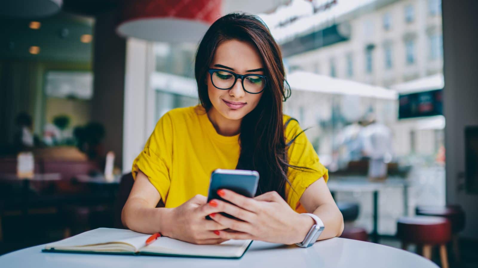 Young woman working on phone in cafe.