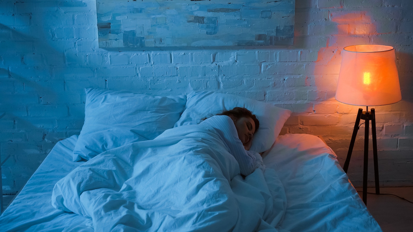 Personal sleeping in bedroom with light on at night.
