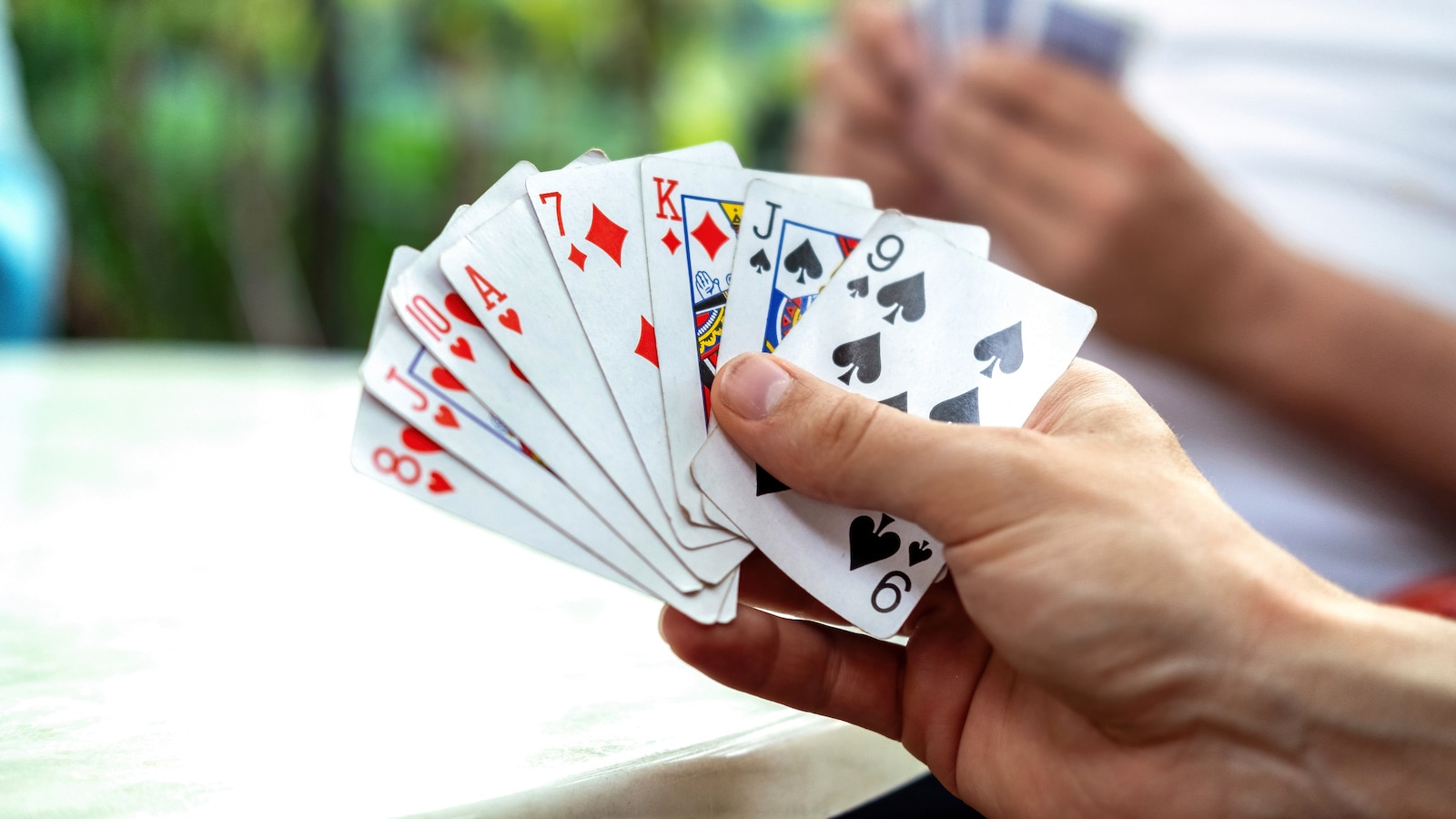 A man playing cards with other people holding a deck.