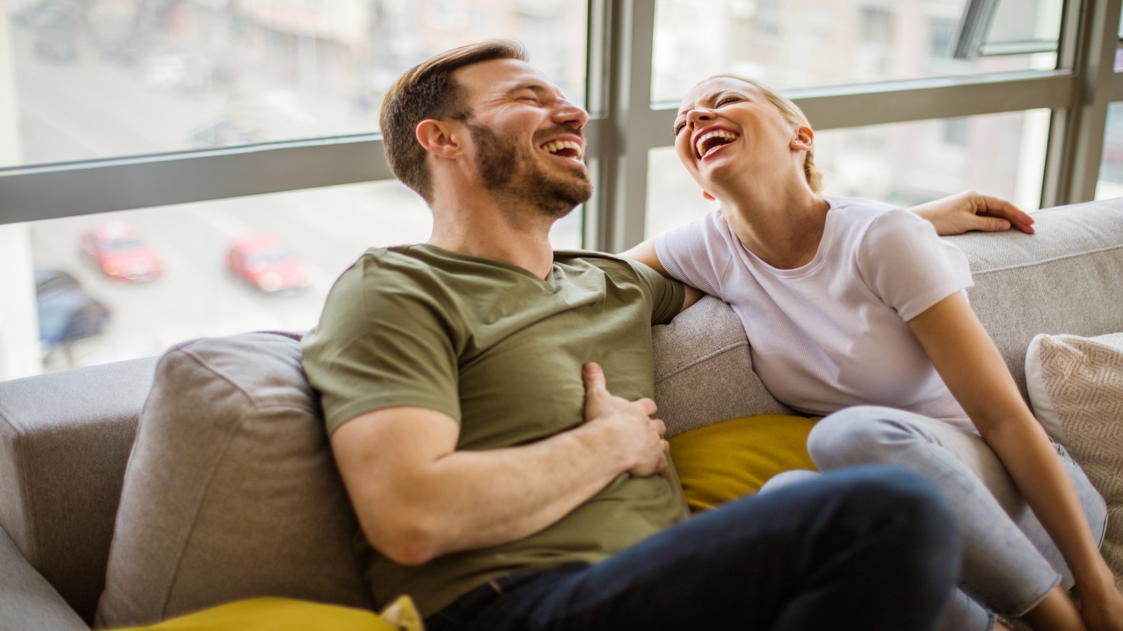 Couple enjoying time together laughing on couch.