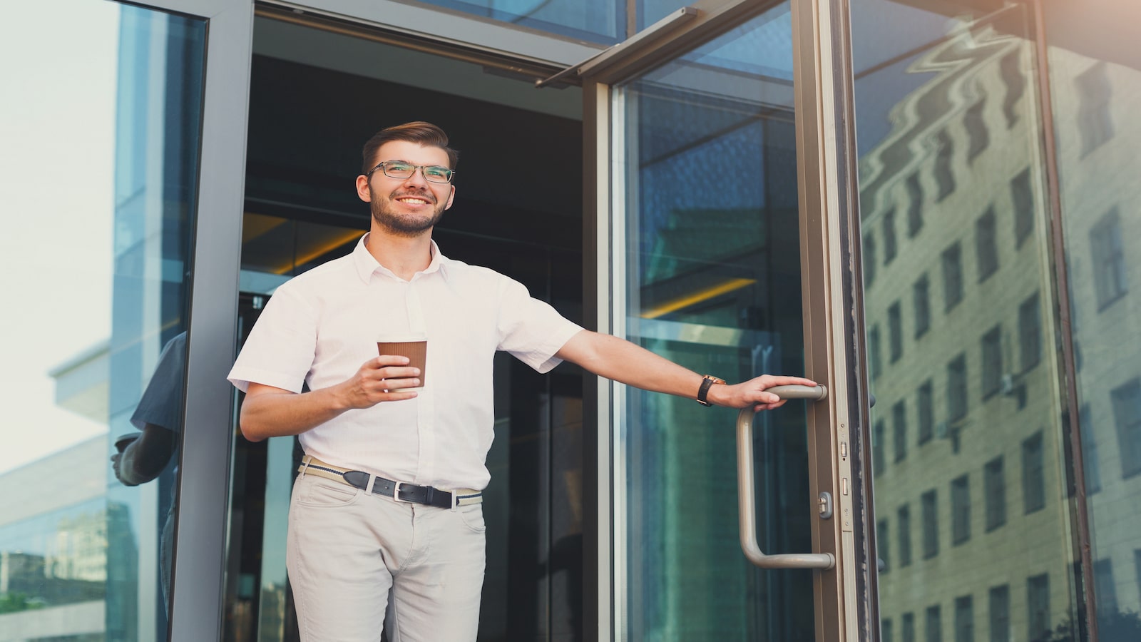 man smiling holding door open.