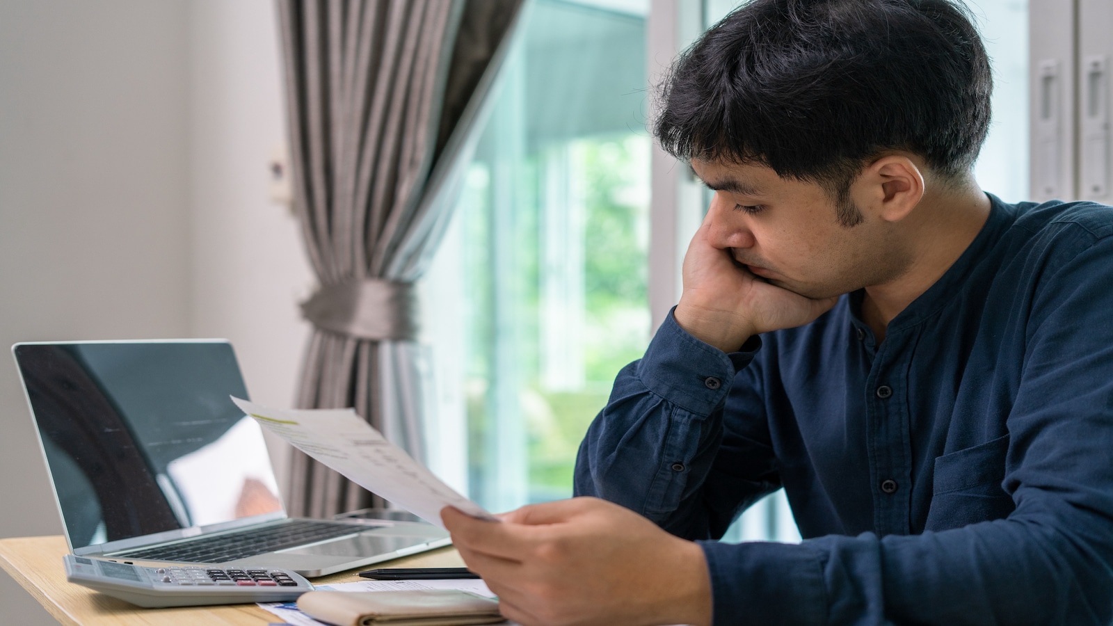 man overwhelmed with credit card bills on table.