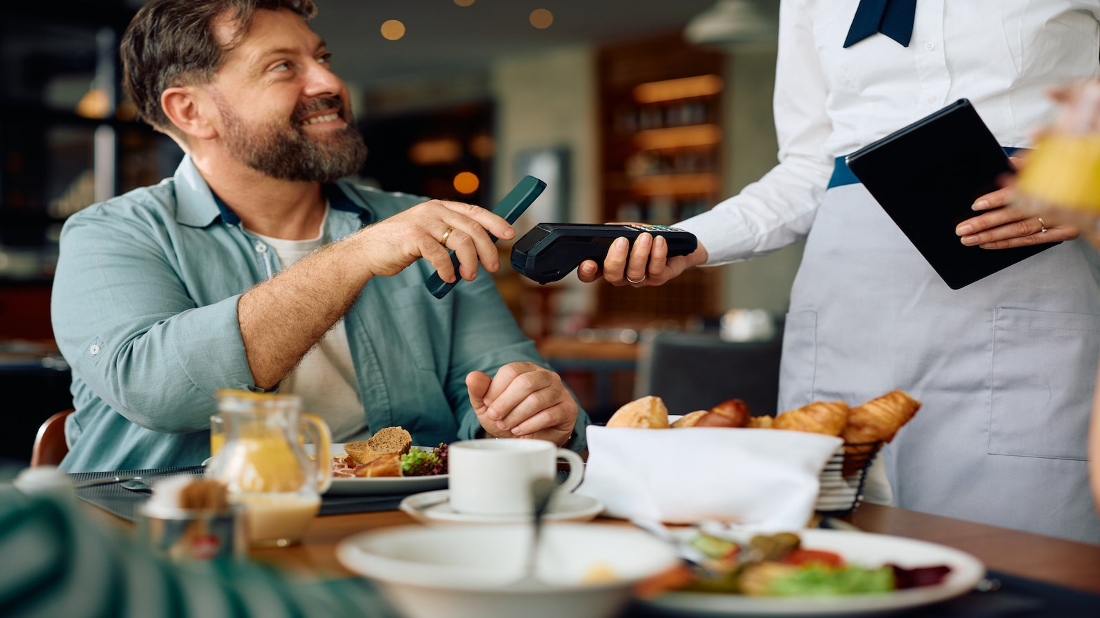 man paying bill with contactless paying and tipping.
