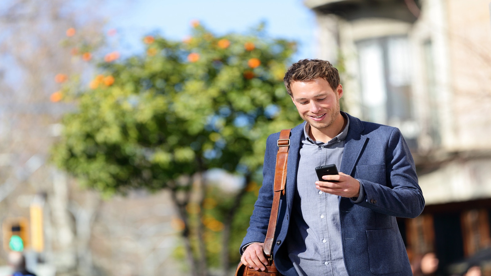 Man walking and checking cell phone sunny day.